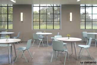 Moderne kantoorruimte met ronde witte tafels, lichtblauwe stoelen, grote raampartijen en groene planten.