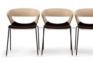 Drie moderne stoelen met beige kunststof rugleuning, zwart zitpad en zwart metalen poten, gerangschikt naast elkaar.
