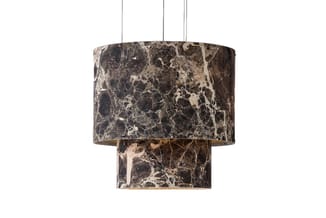Hangende cilindervormige lamp met grijze marmeren structuur, twee geschakelde niveaus en metalen ophangdraden tegen witte ach