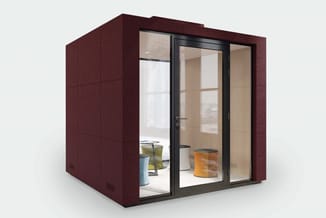 Bordeauxrode akoestische belcel met glazen schuifdeuren en zwart aluminium frame, ingericht met tafel en accessoires.