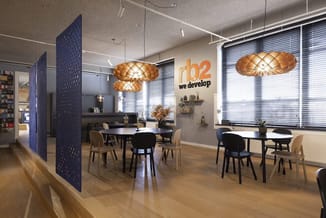 Modern kantoorinterieur met blauwe akoestische schermen, houten hanglampjes, ronde en rechthoekige vergadertafels met zwarte