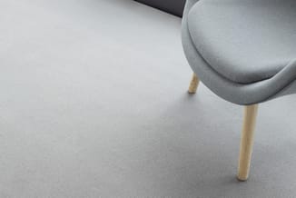 Grijze moderne stoel met ronde zitting en rugleuning, natuurlijke houten poten, bovenaanzicht in heldere ruimte.