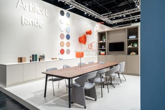 Ardifort showroom met houten vergadertafel, grijze stoelen op wielen, witte kasten, oranje decoratieve objecten en kleurstale