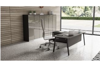 Modern kantoor met zwart bureau, grijze bureaustoel, glazen kastenwand en houten wandbekleding aan glas-in-lood ramen.