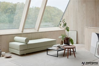 Moderne zithoek met crèmekleurige modulaire bank, houten bijzettafels, zwart metalen salontafel, potplant en boeken onder sch