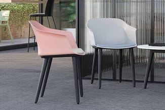 Twee moderne stoelen met zwarte poten in een kantoorruimte: één roze en één lichtblauw, met golvende rugluning.