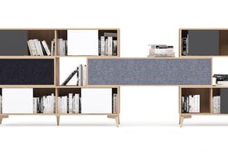Modulair kastensysteem in natuurlijk hout met grijze en donkerblauwe stofafwerkingen, open vakken met boeken en witte deuren.