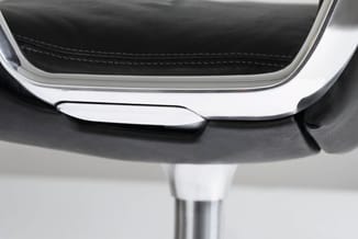 Detailopname van een moderne deurklink in zilver met zwart lederen handgreep en witte chromen beugel.