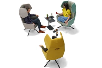 Drie personen zittend in moderne loungestoelen: grijze stoel links, groene stoel rechts, gele stoel voorgrond. Zwart bijzetta