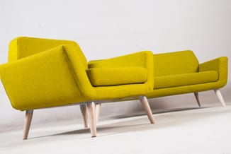 Gele modulaire bank met drie zitdelen, hoekige vormen en lichte houten poten op witte achtergrond.