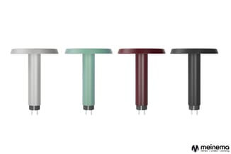 Vier T-vormige tafels in verschillende kleuren: grijs, groen, bordeaux en zwart, met cilindrische poten en metalen voetplaat.