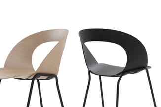 Twee moderne stoelen met gebogen rugleuning: links naturel hout, rechts zwart kunststof, beide op zwart metalen onderstel.