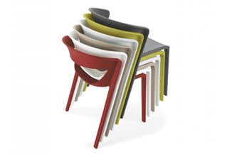 Stapelbare stoelen in verschillende kleuren (rood, wit, beige, geel, grijs, zwart) met moderne vormen, gestapeld tegen elkaar