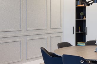 Vergaderruimte met ronde houten tafel, donkerblauwe en grijze stoelen, beige geluidsabsorptiepanelen aan wand, zwarte open ka