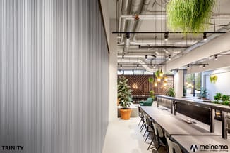 Modern kantoorinterieur met lange werkoppervlakken, zwarte stoelen, hangende planten, houten wandaccenten en industrieel plaf