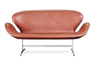 Roodbruine moderne sofa met gebogen armleuningen en metalen U-vormig onderstel op witte achtergrond.