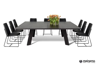 Zwarte vergadertafel met donker houten blad en poten, omringd door zwarte stoelen met metalen frame. Vaas met oranje tulpen i