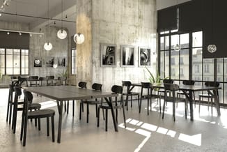 Moderne kantoorruimte met lange grijze vergadertafel, zwarte stoelen, betonnen wanden, hangende glazen verlichtingselementen