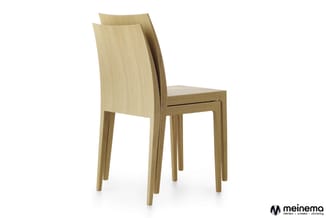 Twee houten stoelen met gebogen rugleuning in natuurlijk fineer, gestapeld tegen elkaar, op witte achtergrond.