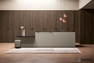 Moderne receptie met licht grijze baliebalie, donkerbruine houten wand, koperen hanglampen, grijs poef, witte bloemen en beig