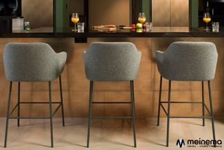 Drie grijze barkrukken met armleuningen en metalen poten aan een houten bar in een modern kantoorinterieur.