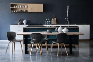 Moderne keuken met zwarte eiland, houten blad, witte onderkasten, drie zwarte stoelen met houten poten, wandkastjes, grijze m