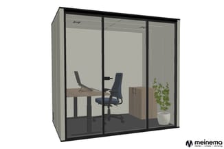 Glazen belcel met zwart frame, werkplek met bureau, bureaustoel, plant en kastje tegen grijze wand.