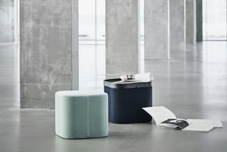 Twee ronde poefs in minimalistische kantoorruimte: één lichtblauw en één donkerblauw, met witte documenten op de vloer.