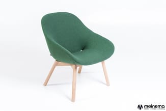 Groene stoel met organische, uitgespaarde rugleuning en naturel houten poten tegen witte achtergrond.