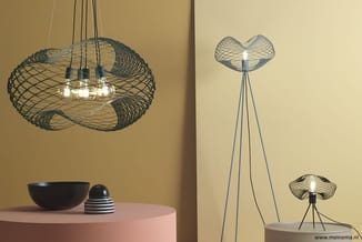 Pendant en vloerlampen met zwart metalen draadkap in organische vorm, geel interieur met accessoires op roze tafel.