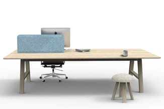 Houten bureau met grijze werkstoel, blauwe scheidingswand, monitor, kleine bijzettafel met beige bekleding en kopje.