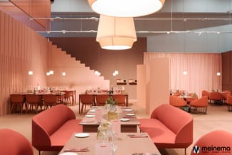 Modern vergaderruimte in koraalrood met curved stoelen, lange vergadertafels, hanglampen en trappenhuisdetail tegen roze wand
