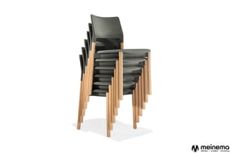 Gestapelde stoelen met zwart leren zitting en rugleuning, natuurhouten frame, gerangschikt op elkaar.