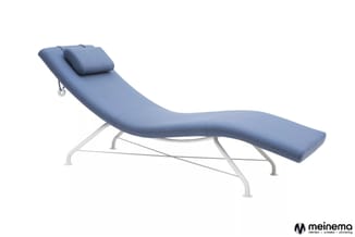 Blauwe chaise longue met voetenbankje, witte metalen onderstel, zwart kussen onder het hoofd.