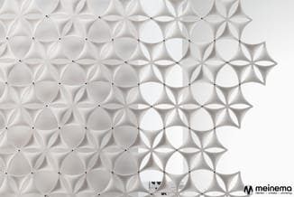 Witte 3D wandpanelen met bloemmotief in geometrische opstelling. Panelen creëren dieptewerking door reliëf. Meinemo-logo zich