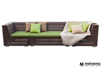 Hoekbank van donkerbruin hout met groene en beige zitkussens, decoratieve kussens en gebreid plaid.