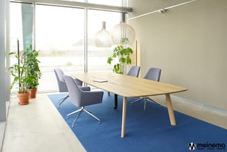 Moderne vergaderruimte met houten tafel, grijze draaistoelen, blauwe tapijt, hangende design-lampen en grote ramen met uitzic