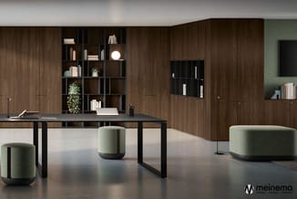 Moderne kantoorruimte met bruine houten kasten, zwart bureau, groene cilindervormige poefs en grijze vloer.