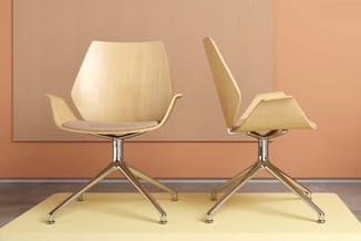 Twee houten designstoelen met armsteunen op chromen driepootonderstel, geplaatst op geel platform tegen beige en oranje achte