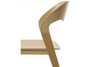Houten stoel met gebogen rugleuning in natuurlijke eiken kleur, zijprofiel tegen witte achtergrond.