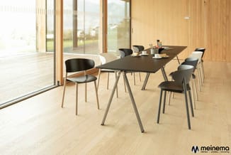 Moderne vergaderruimte met zwarte rechthoekige tafel, grijze poten, zwarte en witte stoelen, lichte houten vloer en grote gla