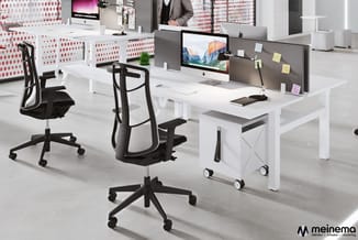Modern kantoor met witte werkbanken, grijze scheidingswanden met gele notities, zwarte bureaustolen en een iMac-display. Mein