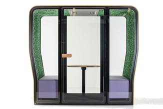 Akoestische telefooncel met zwart frame, groene akoestische binnenwanden, paarse zittingen en houten tafel in het midden.