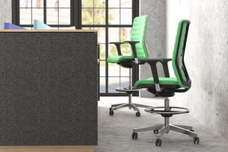 Moderne kantoorruimte met twee groene ergonomische bureaustoel met zwart frame, grijze akoestische wand en ramen op achtergro