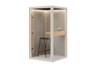 Akoestische belcel met lichte houten frame, grijze stofwanden, zwarte barkruk, ingebouwde verlichting en werkblad met laptop.