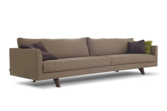 Grijsbruine loungebank met twee zitplaatsen, houten poten, decoratieve kussens in paars en groen, moderne design.