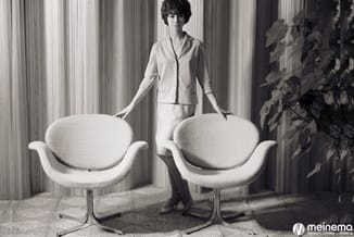 Twee witte moderne fauteuils met organische vorm en metalen voet in minimalistische interieur, met vrouw in beige kostuum era