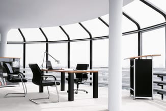 Modern kantoor op hoogte met glazen wanden, witte zuilen, houten bureau met zwarte onderstel, zwarte bureaustoelen en design