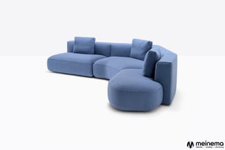 Blauwe hoekbank met ronde en organische vormen, uitgevoerd in stofbekleding, met losse kussens.