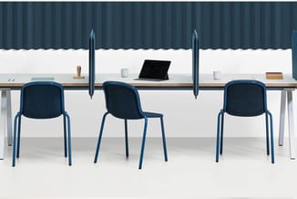 Kantoorwerkplek met drie blauwe stoelen aan lange tafel, tablet, kopjes en accessoires tegen gestreepte muur.